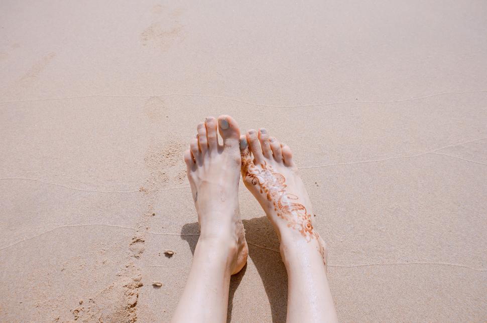 Free Image of Person Standing on Beach With Feet in Sand 
