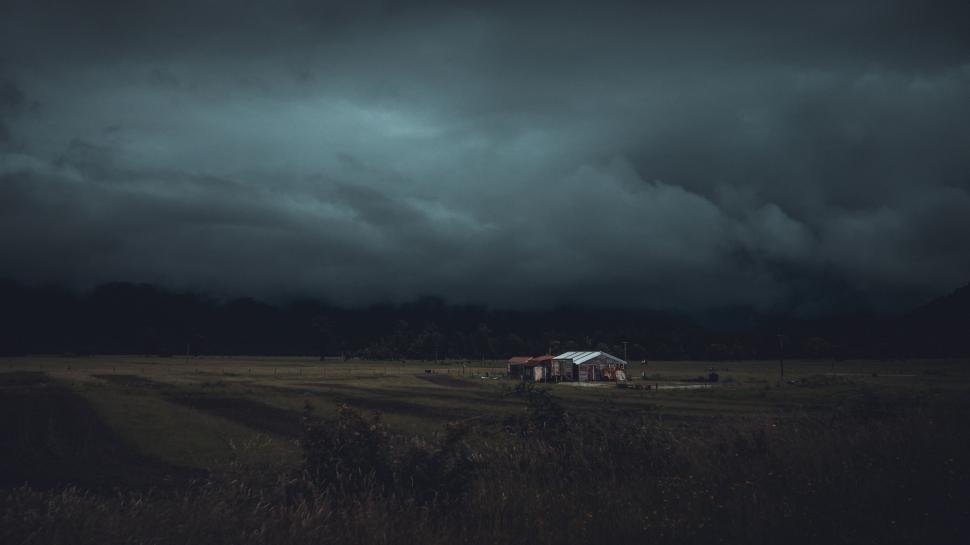 Free Image of House Amid Field Under Dark Sky 
