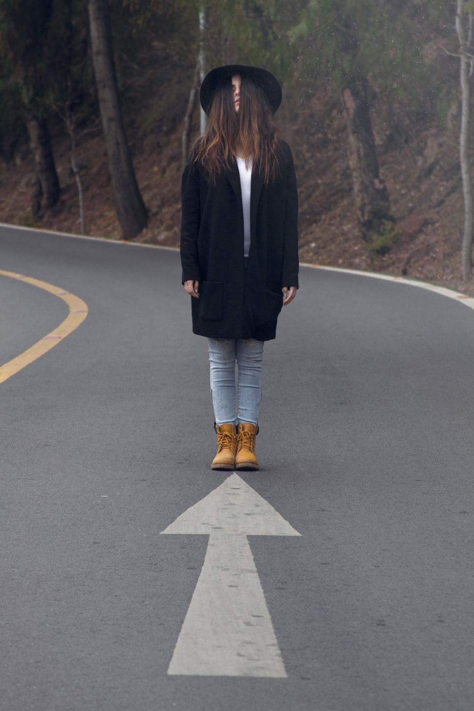 Free Image of Woman Standing on Road With Arrow 