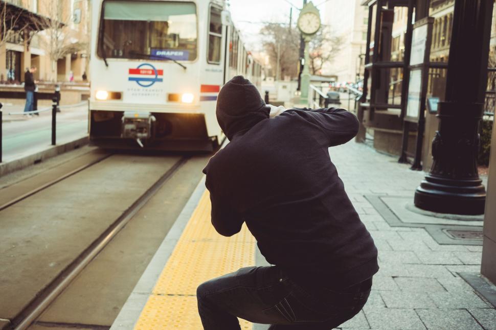 Free Image of Man Squatting on Platform in Front of Train 