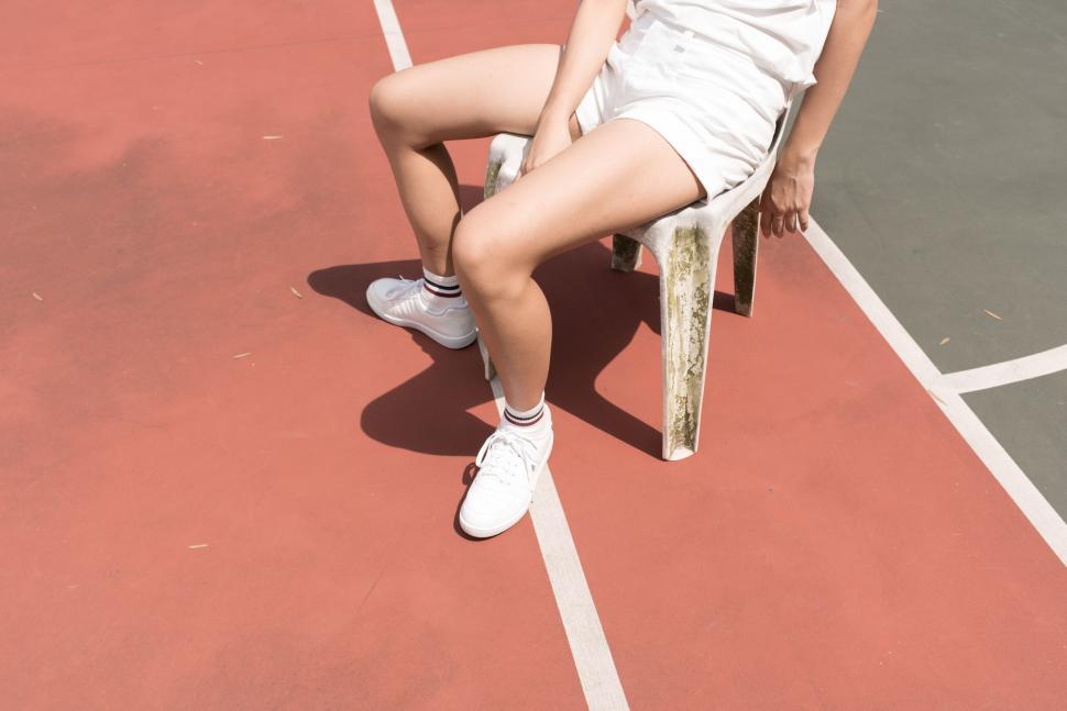 Free Image of Woman Sitting on Tennis Court Holding Racquet 