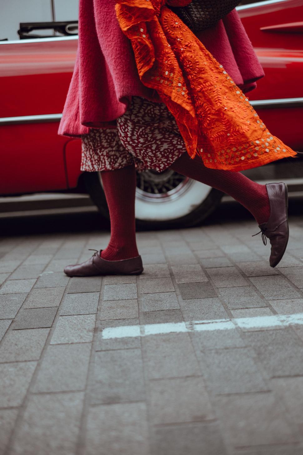 Free Image of Woman in Red Coat Walking by Red Car 