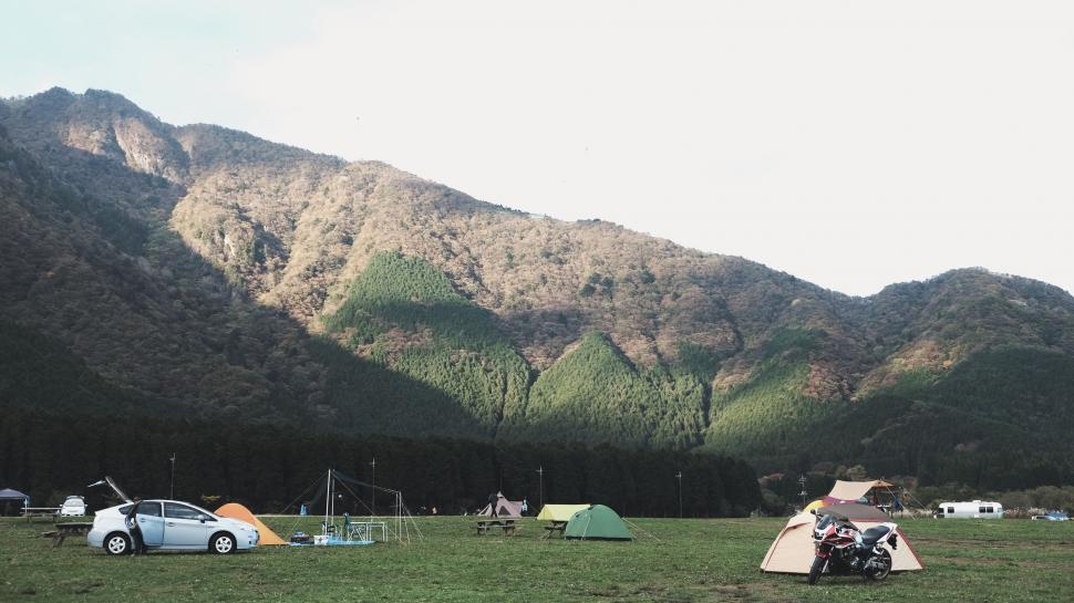 Free Image of Group of Tents in Field With Mountains in Background 
