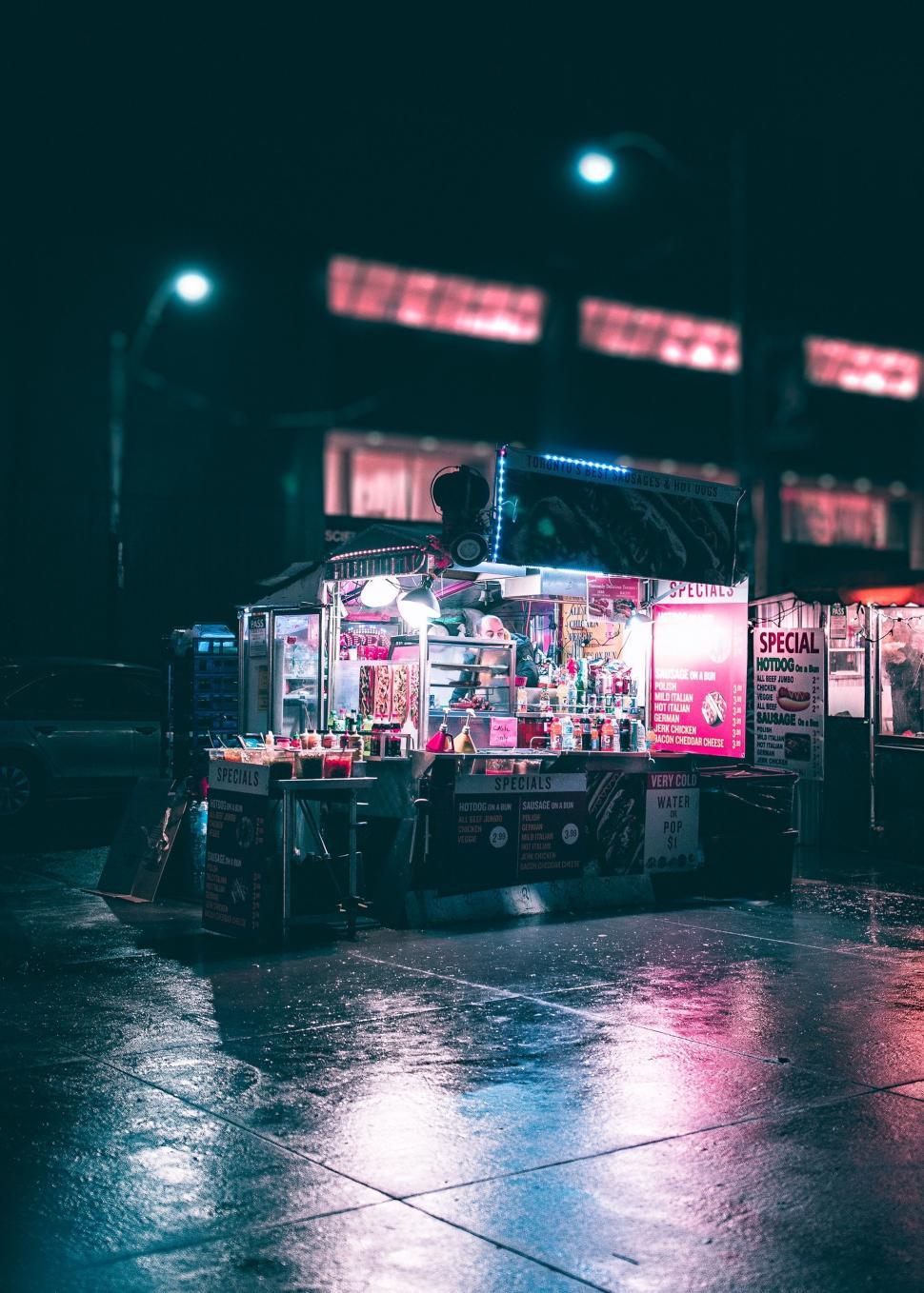 Free Image of Street Vendor Standing in Rain at Night 
