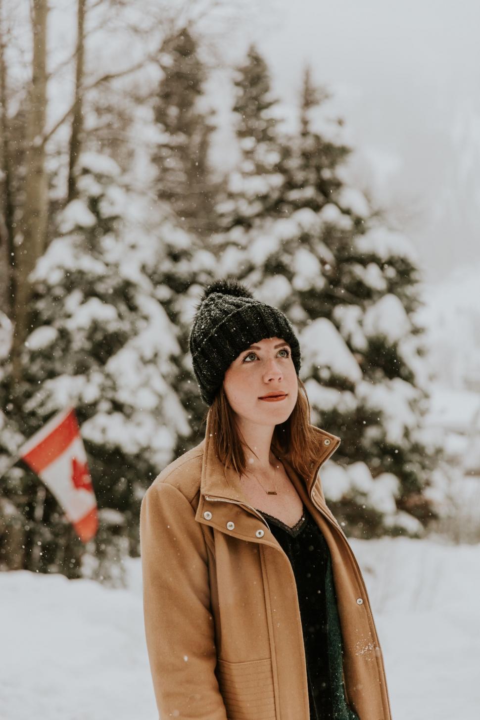 Free Image of Woman Standing in Snow With Canadian Flag in Background 