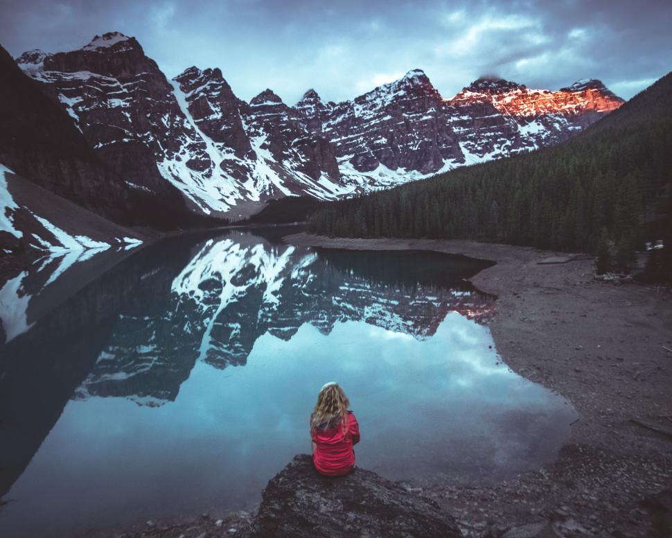 Free Image of Person in Red Jacket Sitting on Rock Near Lake 