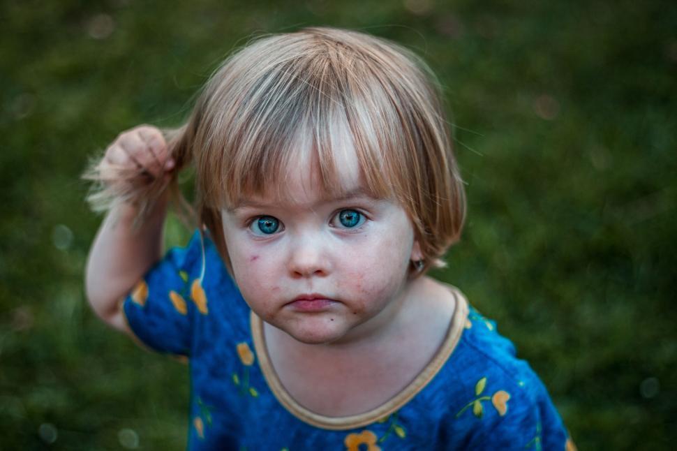 Free Image of Little Girl With Blue Eyes Holding Her Hair Up 