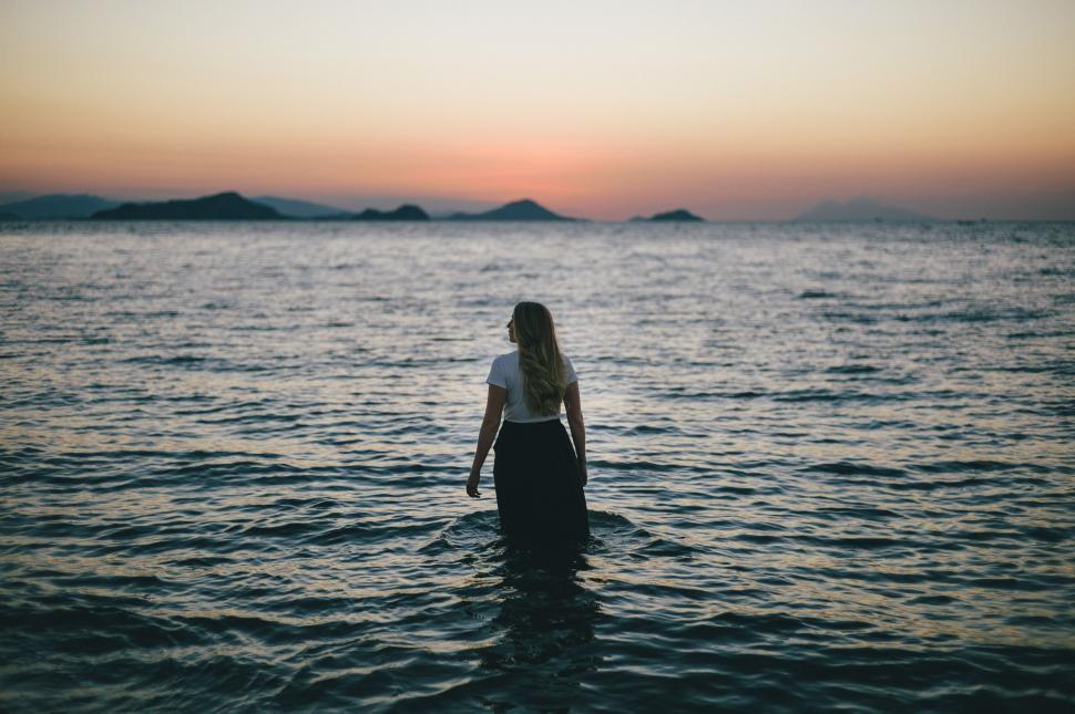 Free Image of Woman Standing in Ocean at Sunset 
