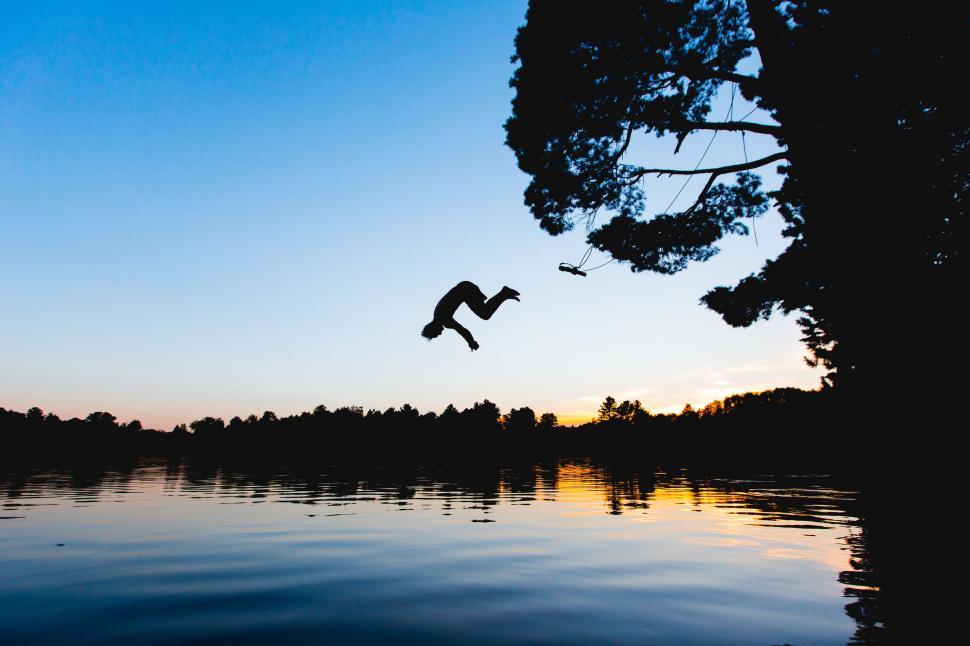 Free Image of Person Jumping Into Lake at Sunset 