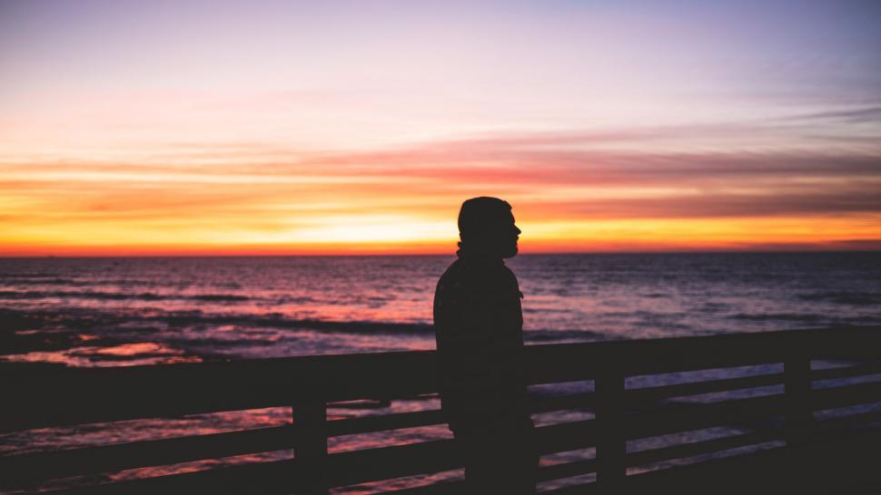 Free Image of Man Standing on Pier Watching Sunset 