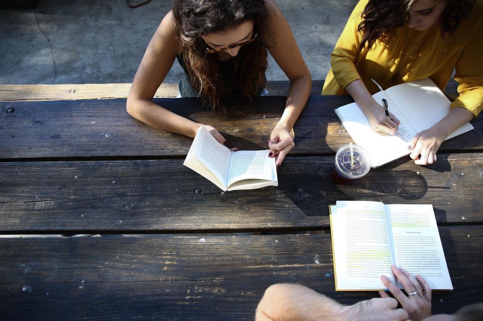 Free Image of Two Women Sitting at a Table With Open Books 