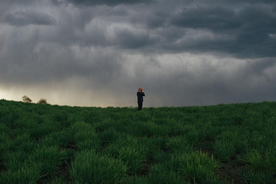 Free Image of Person Standing in Field Under Cloudy Sky 