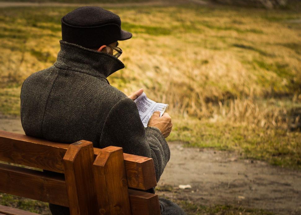 Free Image of Man Sitting on Bench Reading Newspaper 