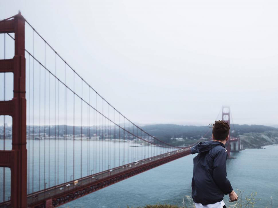Free Image of Man Standing on Hill Looking at Bridge 