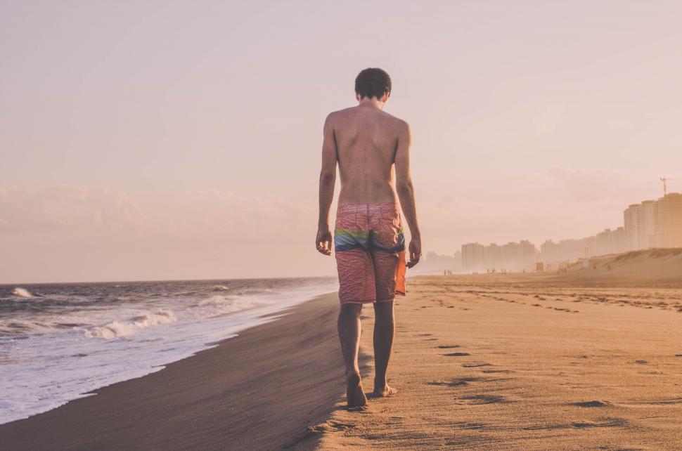Free Image of Man Walking Along Beach by Ocean 