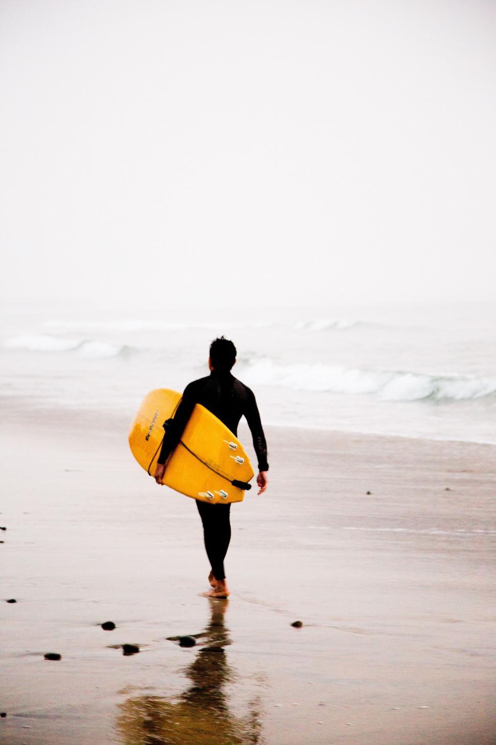 Free Image of Man Carrying Yellow Surfboard on Beach 