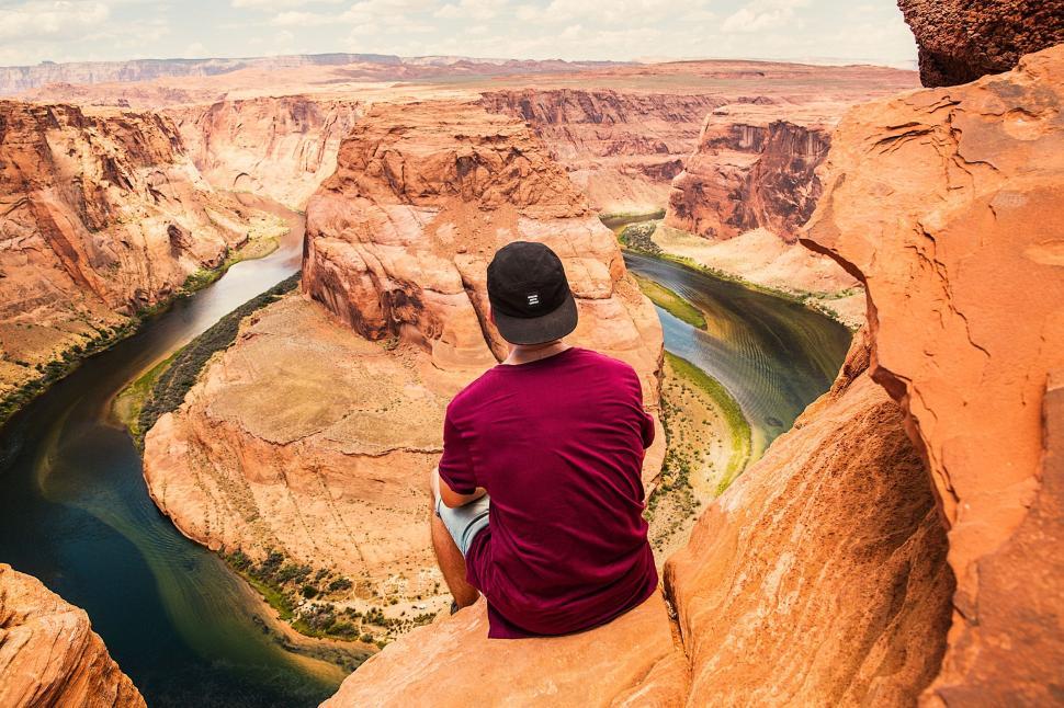Free Image of Man Sitting on Cliff Overlooking River 