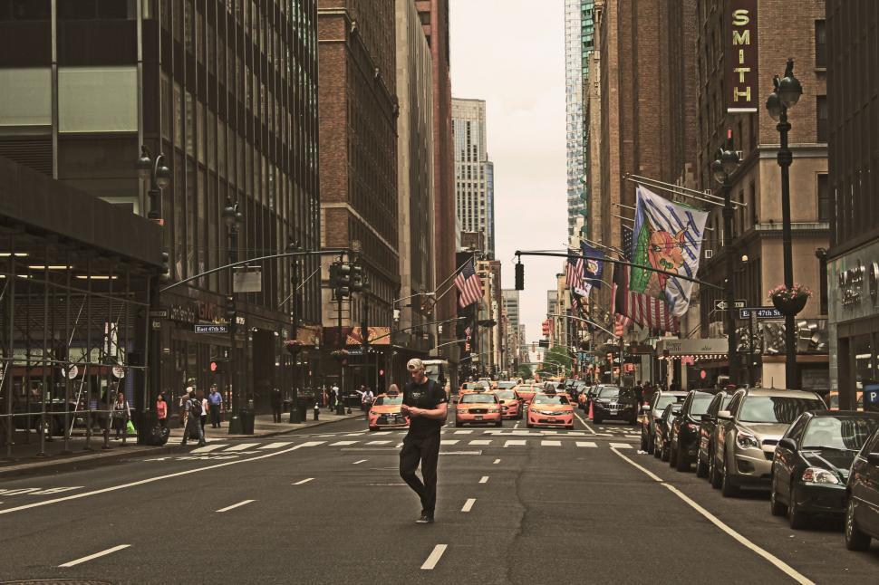Free Image of Man Walking Down Street Next to Tall Buildings 