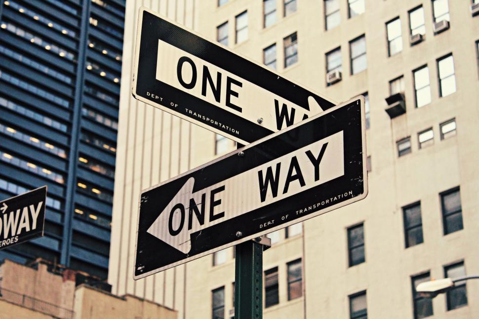 Free Image of One Way Street Sign in Front of Tall Building 