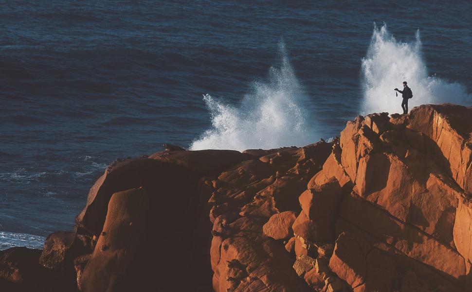Free Image of Person Standing on Top of Rock Near Ocean 