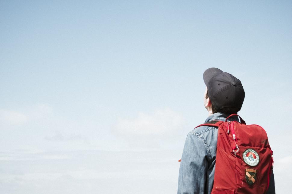 Free Image of Person With Red Backpack Looking at the Sky 