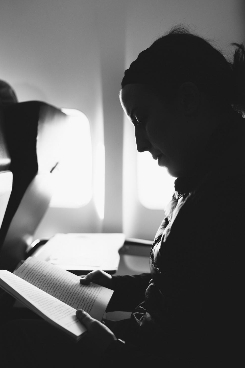 Free Image of Woman Sitting on Airplane Reading Book 
