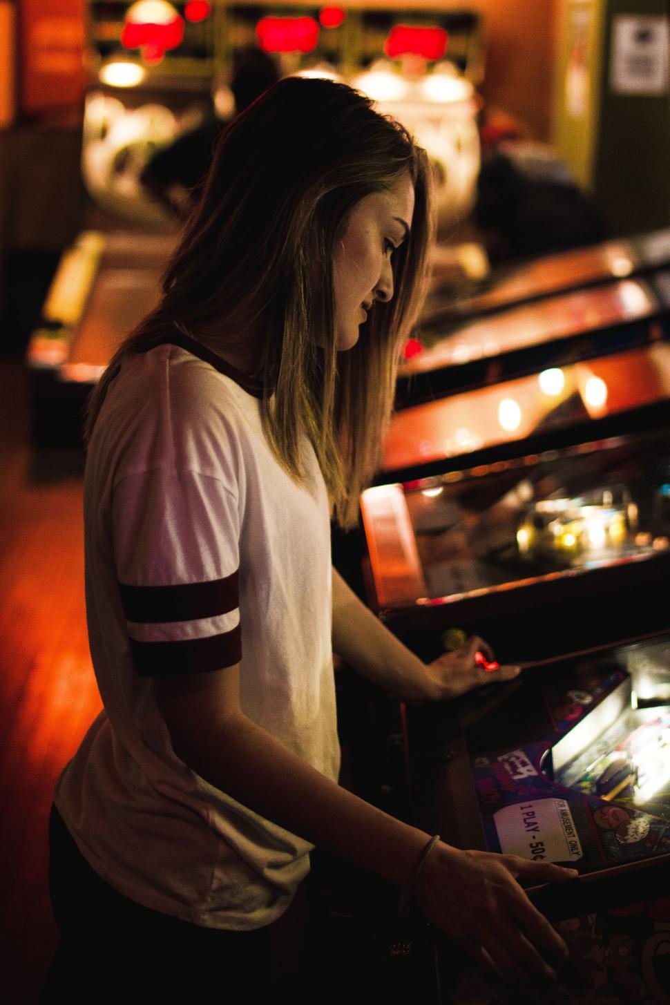 Free Image of Woman Standing in Front of Pinball Machine 