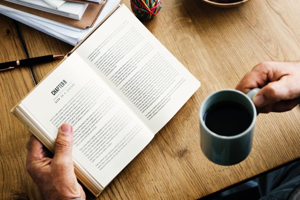 Free Image of Person Sitting at Table With Book and Coffee 