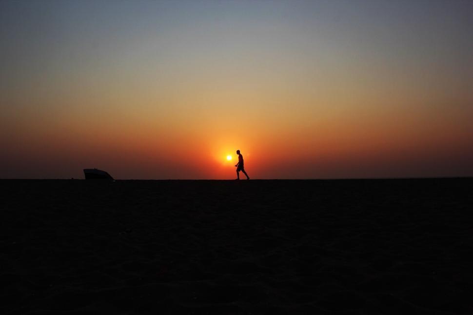 Free Image of Person Walking Across Field at Sunset 