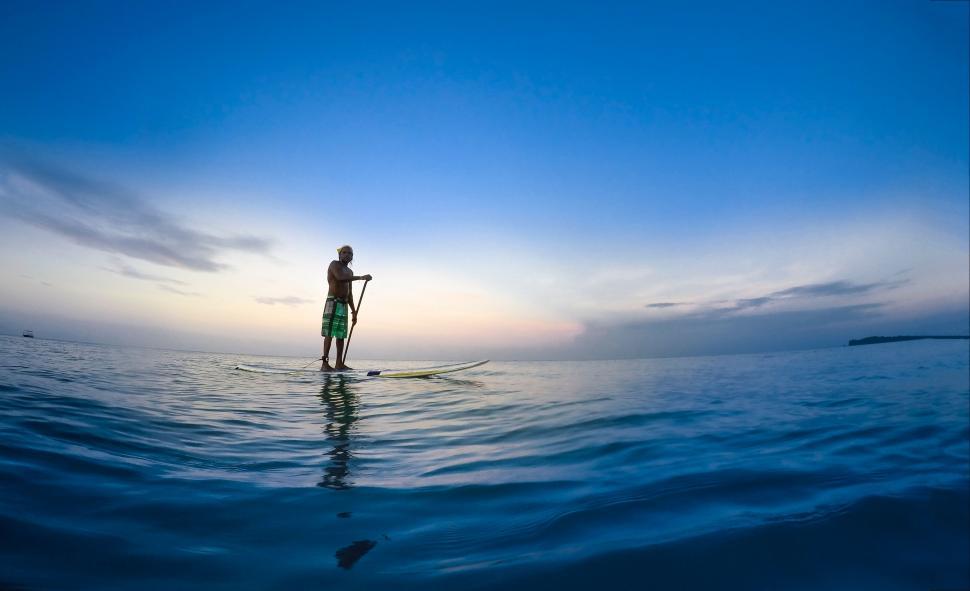 Free Image of Man Standing on Surfboard in Ocean 
