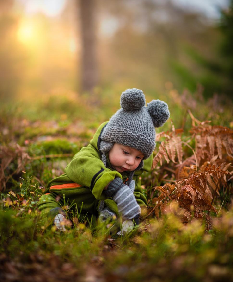 Free Image of Little Boy Sitting in Grass Wearing Hat 