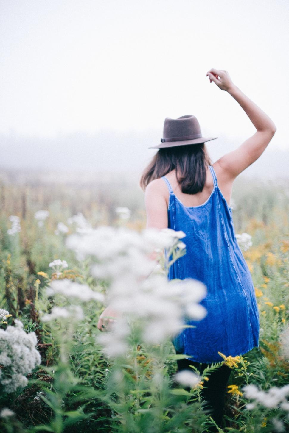 Free Image of Woman in Blue Dress and Hat in Field of Flowers 