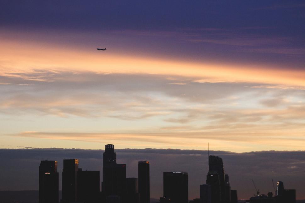 Free Image of Plane Flying Over City at Sunset 
