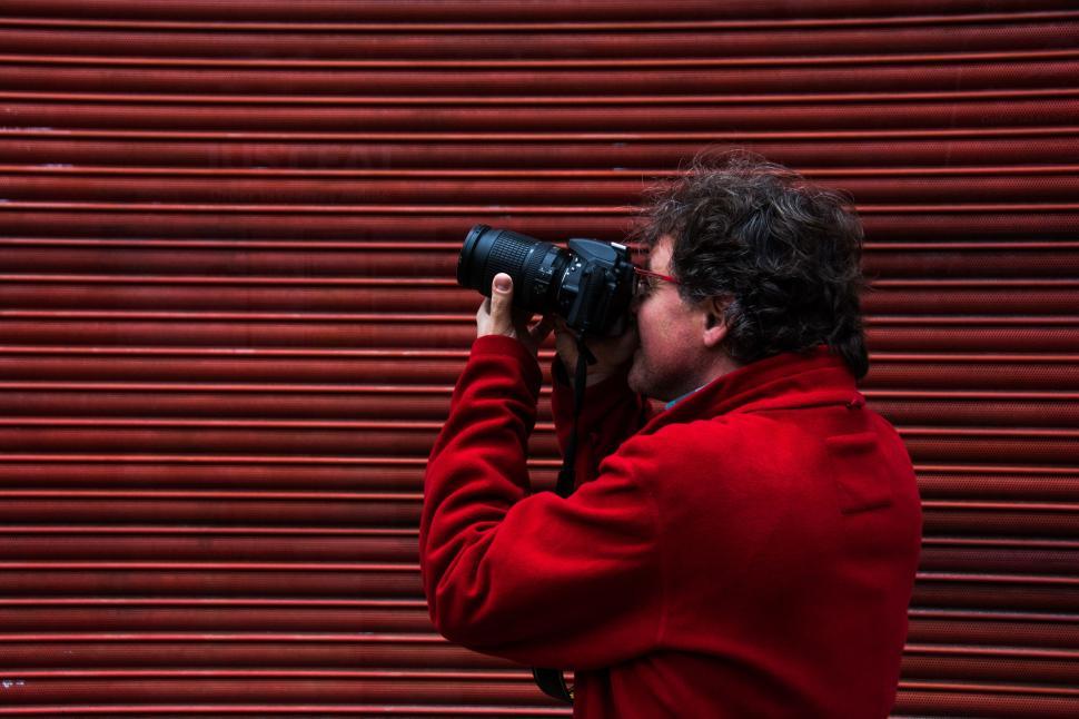 Free Image of Man in Red Jacket Taking Picture With Camera 