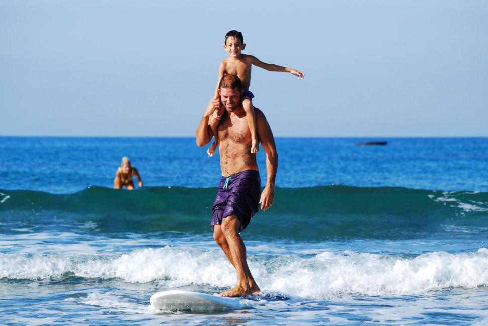 Free Image of Man Holding Child on Surfboard in Ocean 
