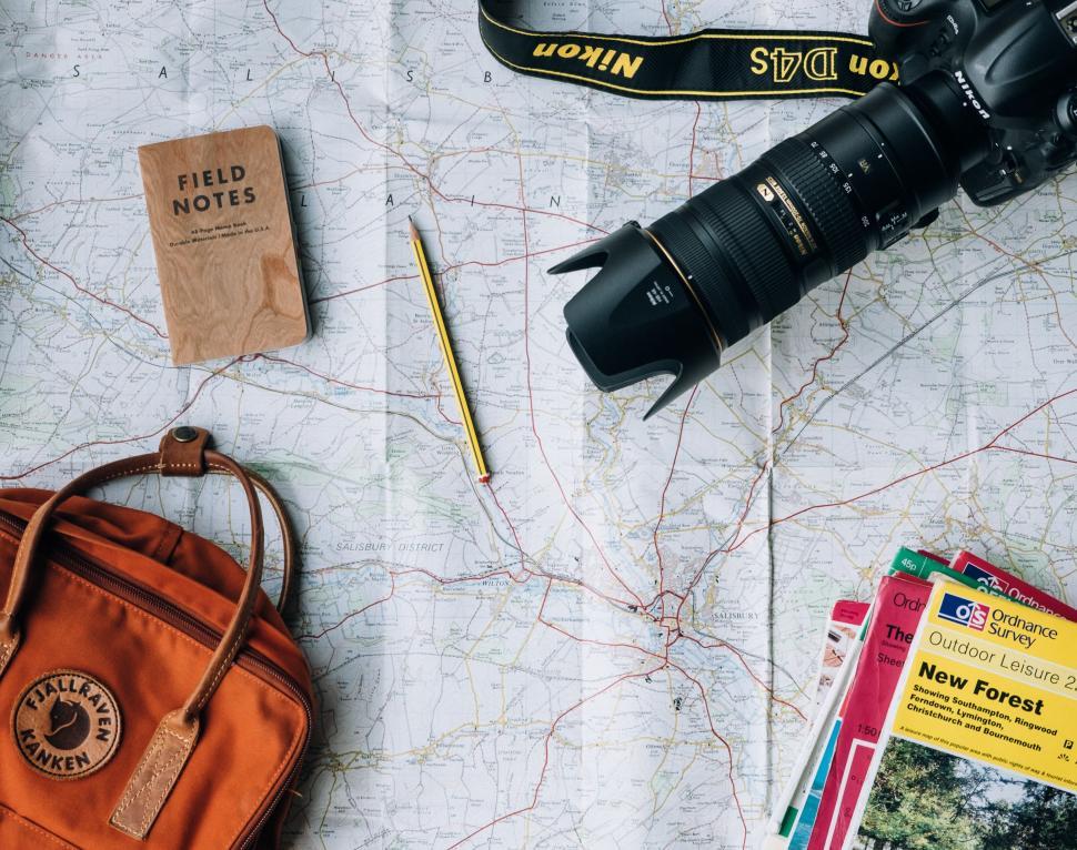 Free Image of A Map, a Camera, a Book, a Pen, and Miscellaneous Items 