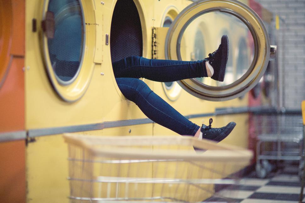 Free Image of Woman Sitting on Ledge in Front of Washing Machine 
