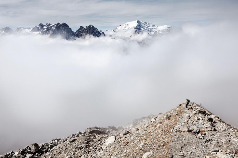 Free Image of Person Standing on Top of a Mountain Above the Clouds 