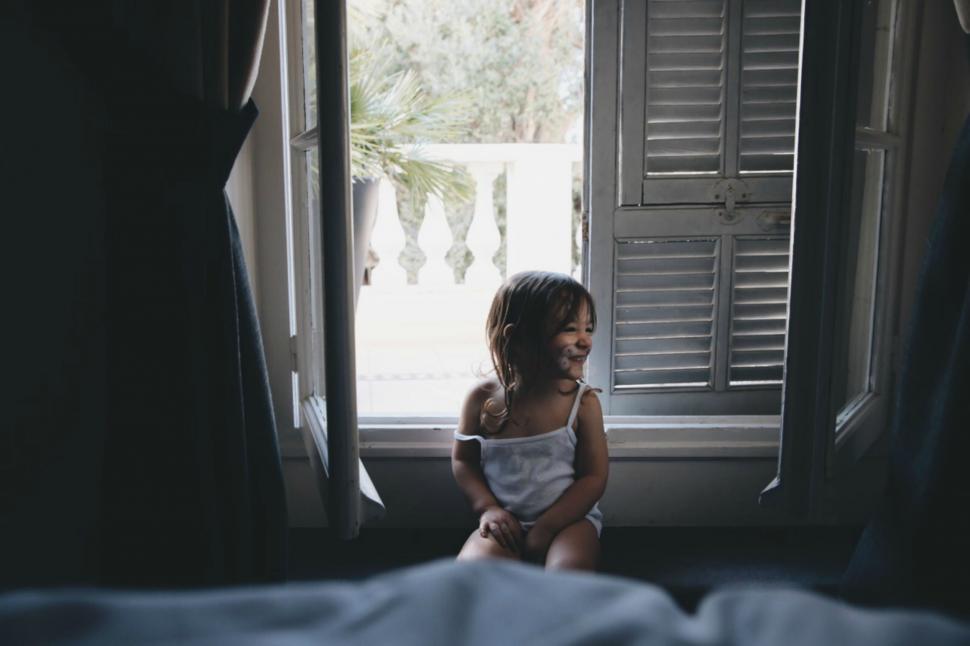 Free Image of Little Girl Sitting in Front of Window 