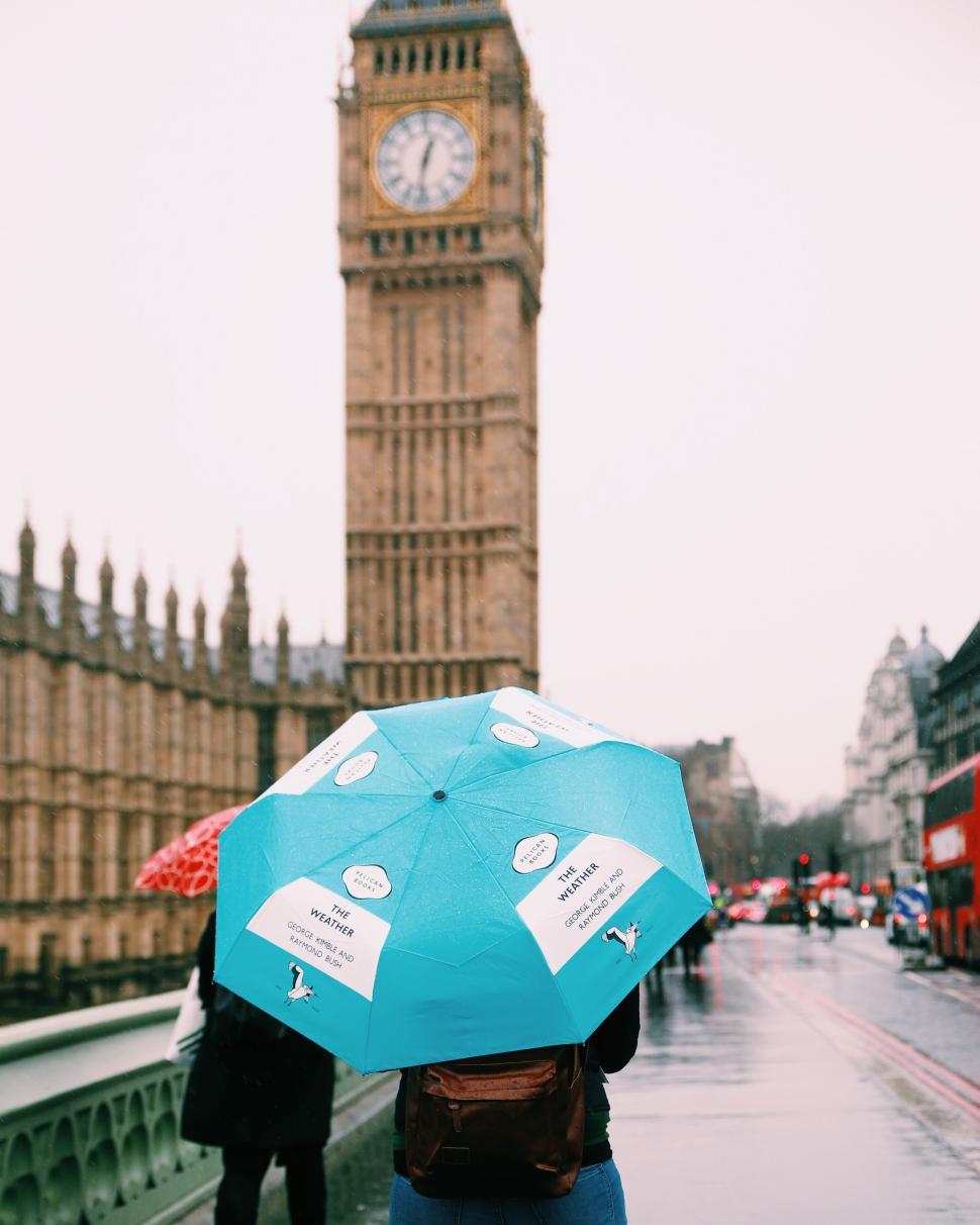 Free Image of Person Holding Blue Umbrella in Front of Clock Tower. 