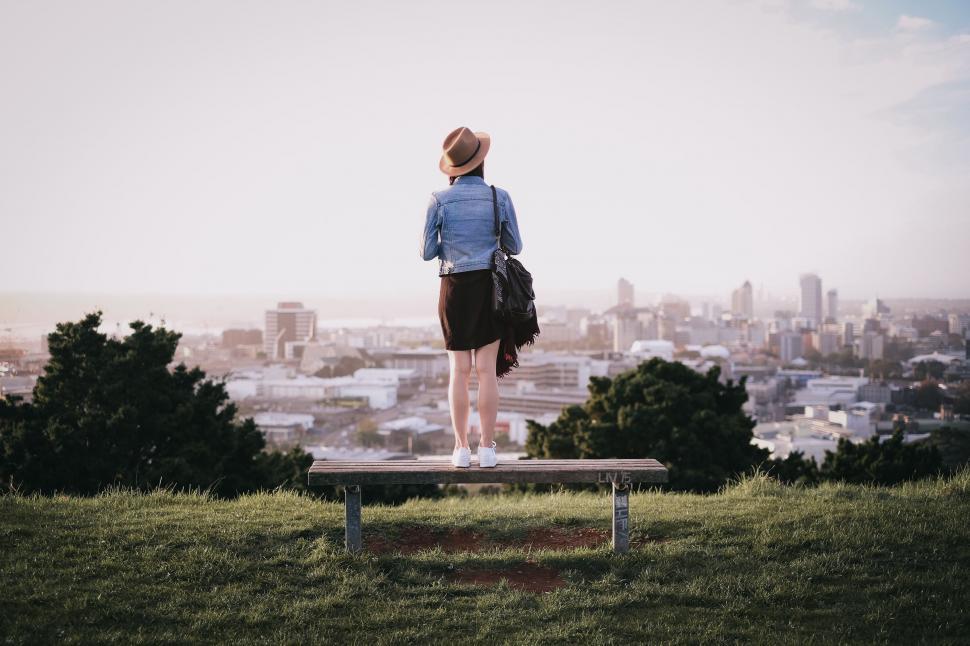 Free Image of Woman Standing on Bench Overlooking City 