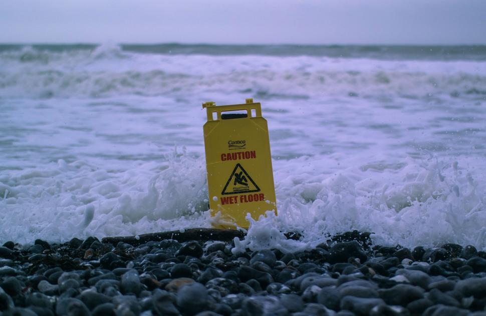 Free Image of Yellow Caution Sign on Rocky Beach 