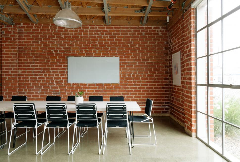 Free Image of Room With Brick Wall and White Table With Black Chairs 
