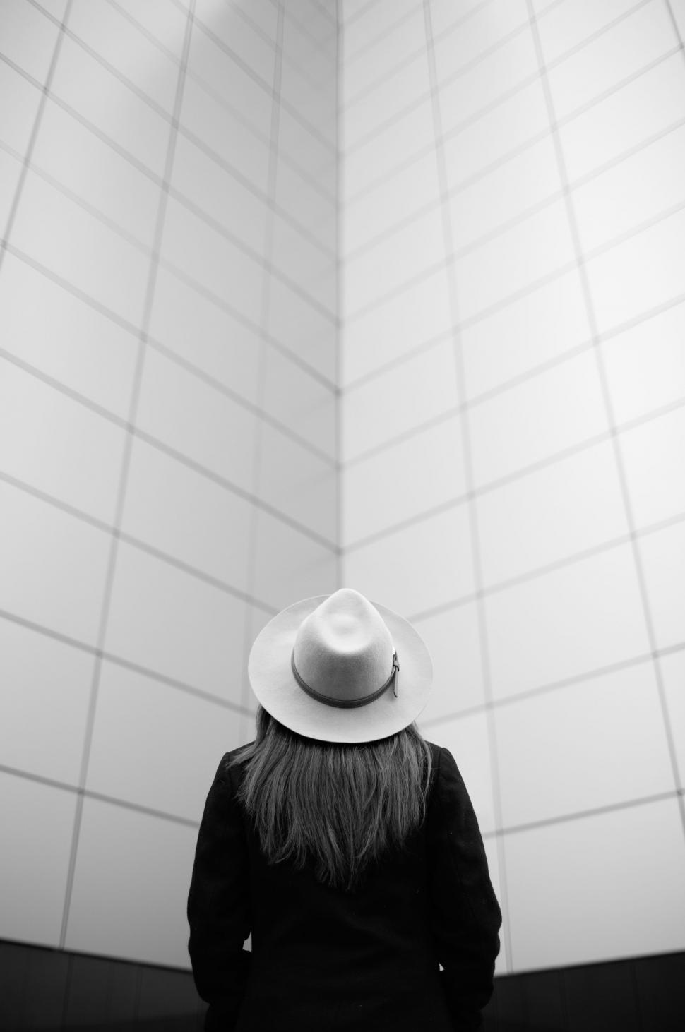 Free Image of Woman With Hat Standing in Front of Tiled Wall 