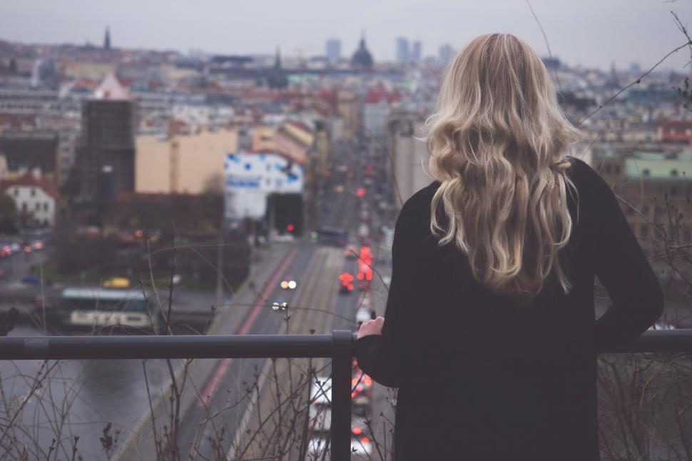 Free Image of Woman Standing on Balcony Looking Out Over City 