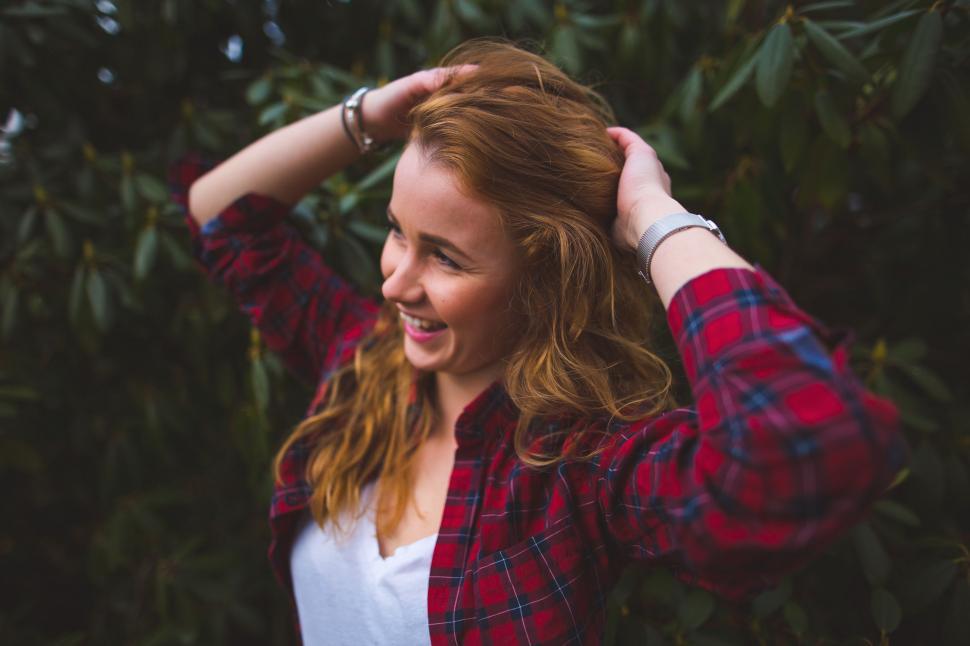 Free Image of Smiling Woman With Red Hair Holding Hands Behind Head 
