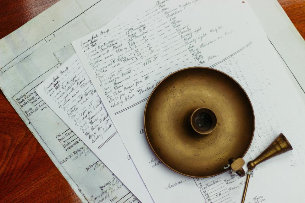 Free Image of Brass Plate Resting on Papers on Wooden Table 