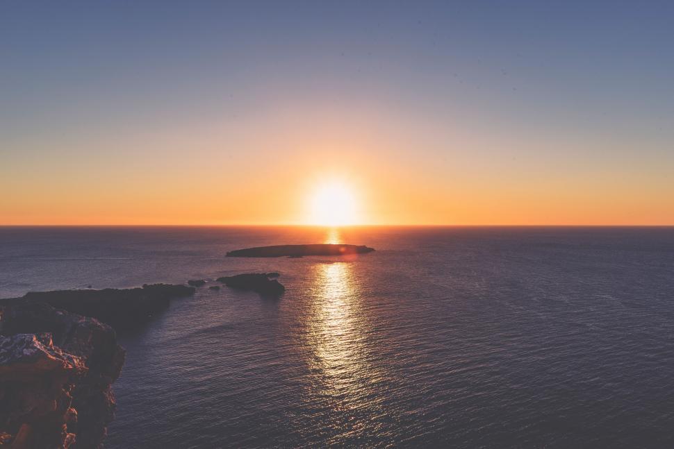 Free Image of Sun Setting Over Ocean With Small Island 