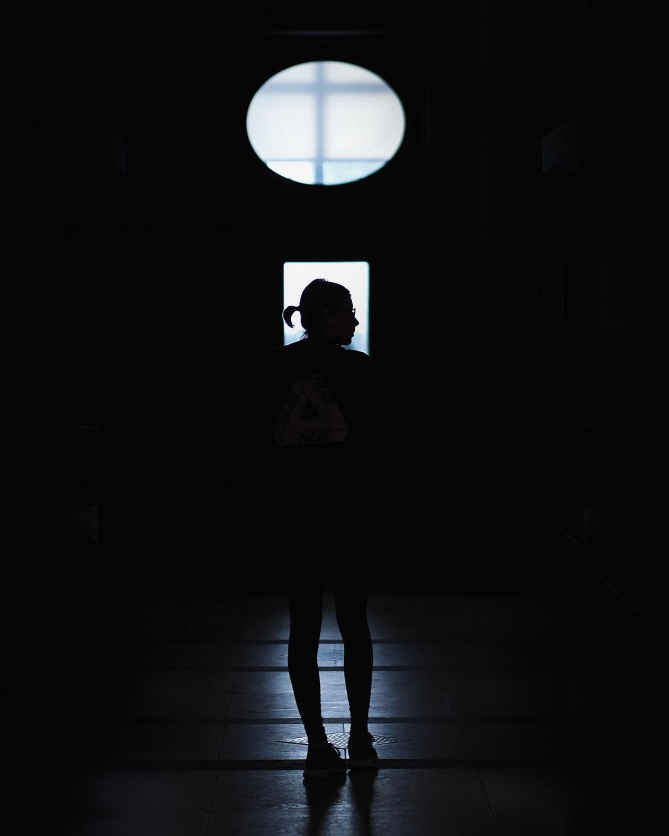 Free Image of Silhouette of a Person Standing in a Dark Room 