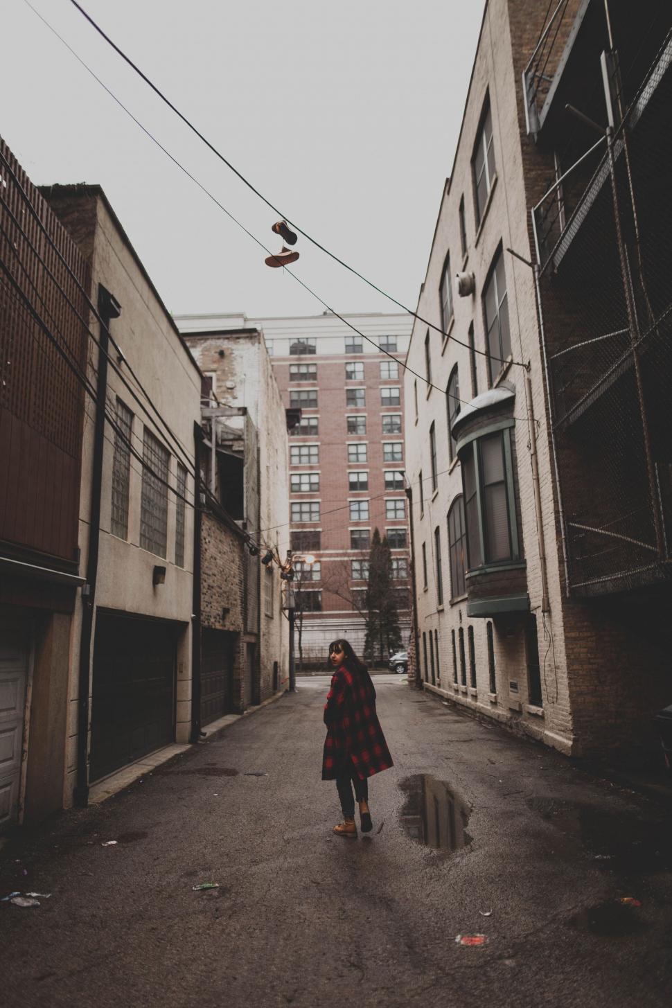 Free Image of Woman Walking Down a City Street Next to Tall Buildings 